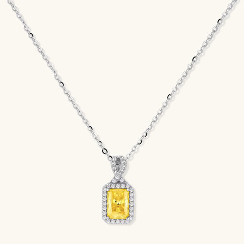 Rectangular yellow moissanite pendant in sterling silver halo setting on delicate chain against cream background.