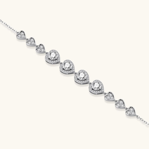Sterling silver bracelet with graduated heart-shaped links and sparkling moissanite stones in VVS1 clarity on white background.
