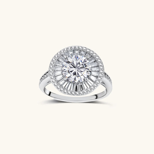 Brilliant round moissanite center stone with baguette and round halo accents in sterling silver setting on light background.