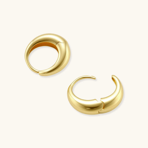 Chunky gold-plated sterling silver huggie hoop earrings with hinged closure mechanism on cream background.