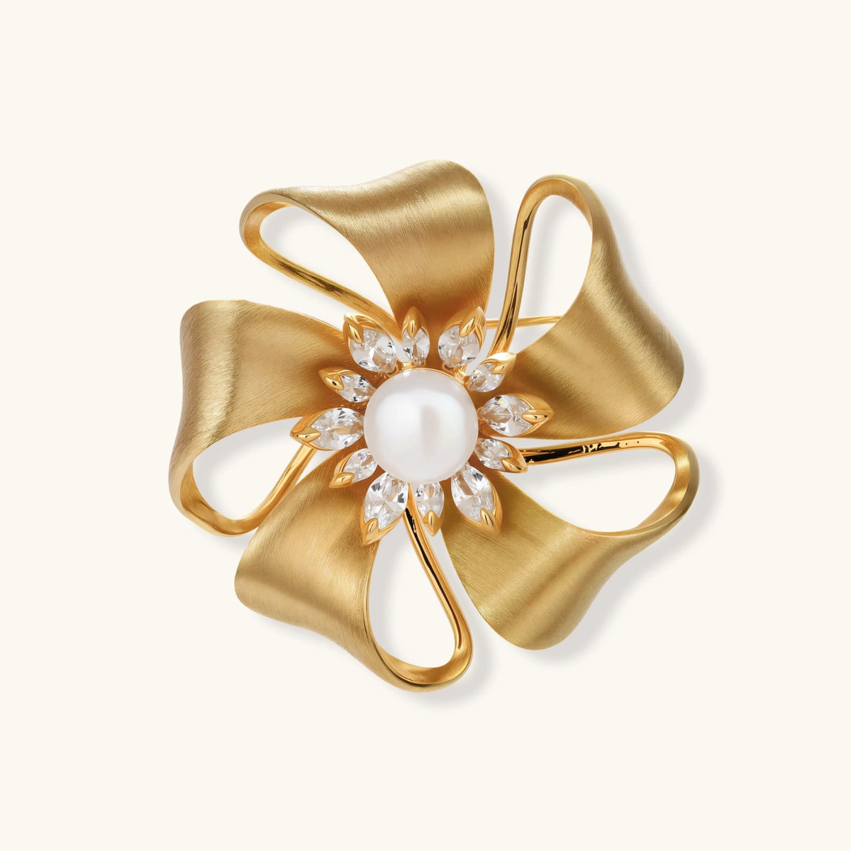 18K gold-plated bow brooch with dimensional ribbon design, pearl center, and sparkling zircon stones on white background.