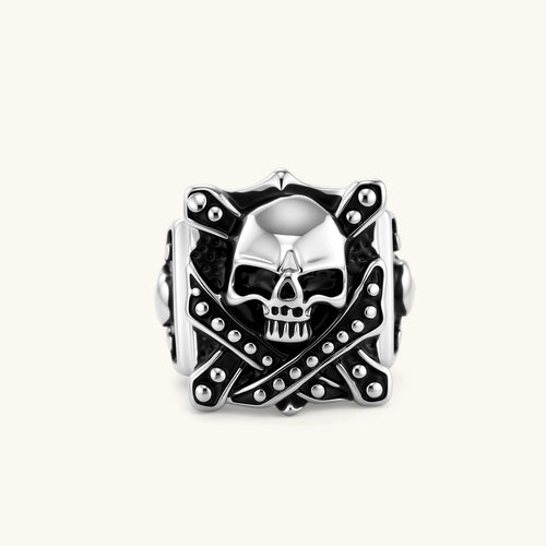 Silver-tone 316L stainless steel skull ring with crossbones, black enamel fill, studded details, and wide shank, 21mm top width.
