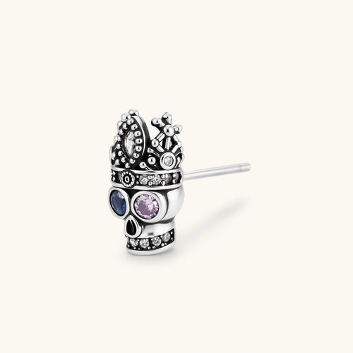 316L stainless steel skull stud earring with ornate crown top, blue and pink CZ eyes, and clear CZ accents on white background.