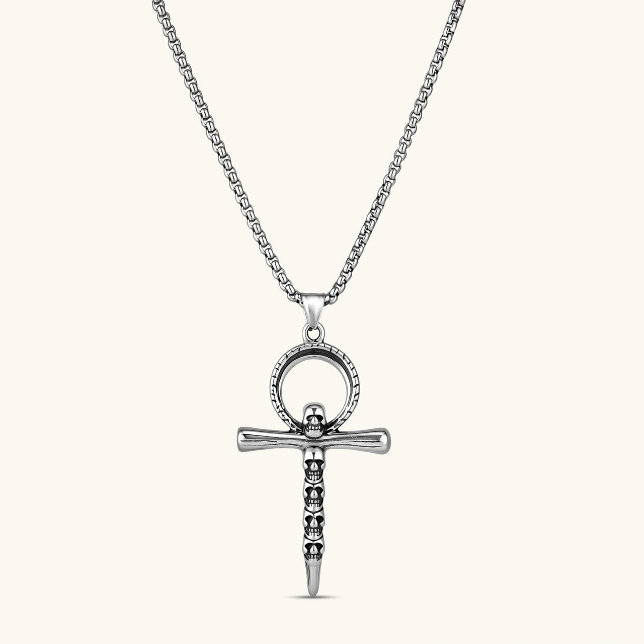 Silver stainless steel ankh pendant with skull motifs on vertical bar and textured ring top, on a box chain necklace.