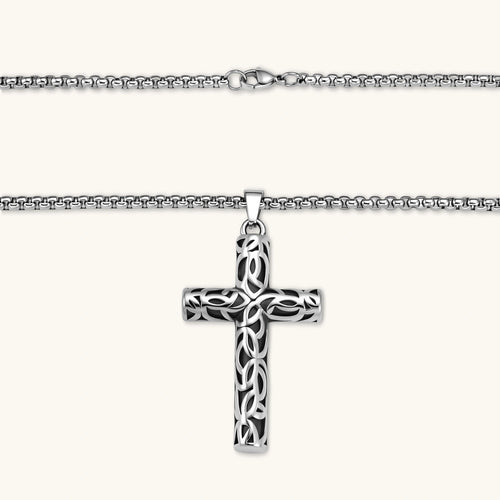 Silver stainless steel Celtic cross pendant with filigree vine pattern on a box chain, against a cream background.