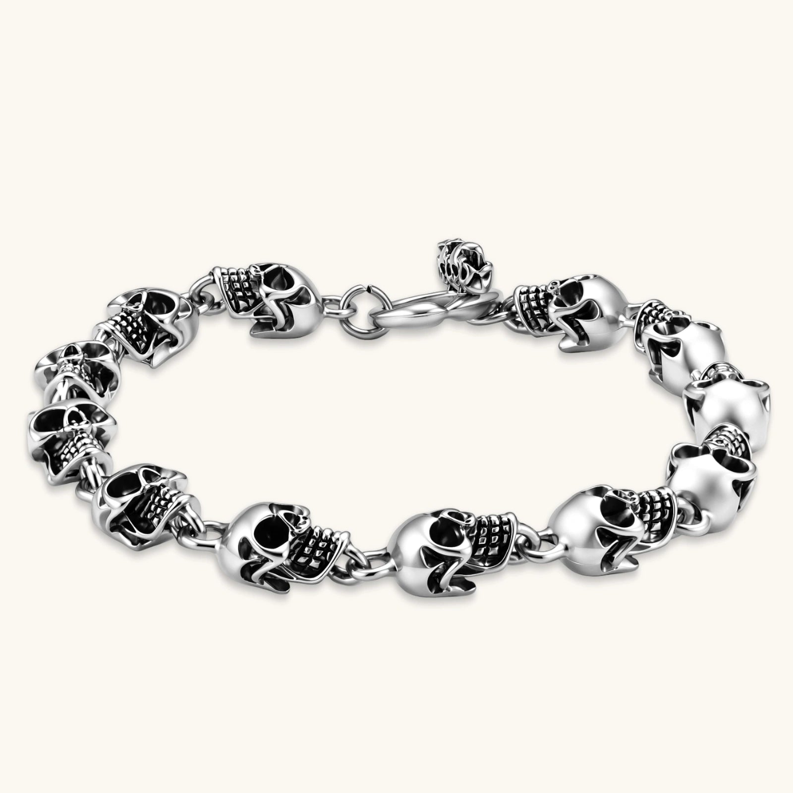 Silver stainless steel bracelet with linked 3D skull charms and a spring-ring clasp, oxidized black detailing, 225mm length.
