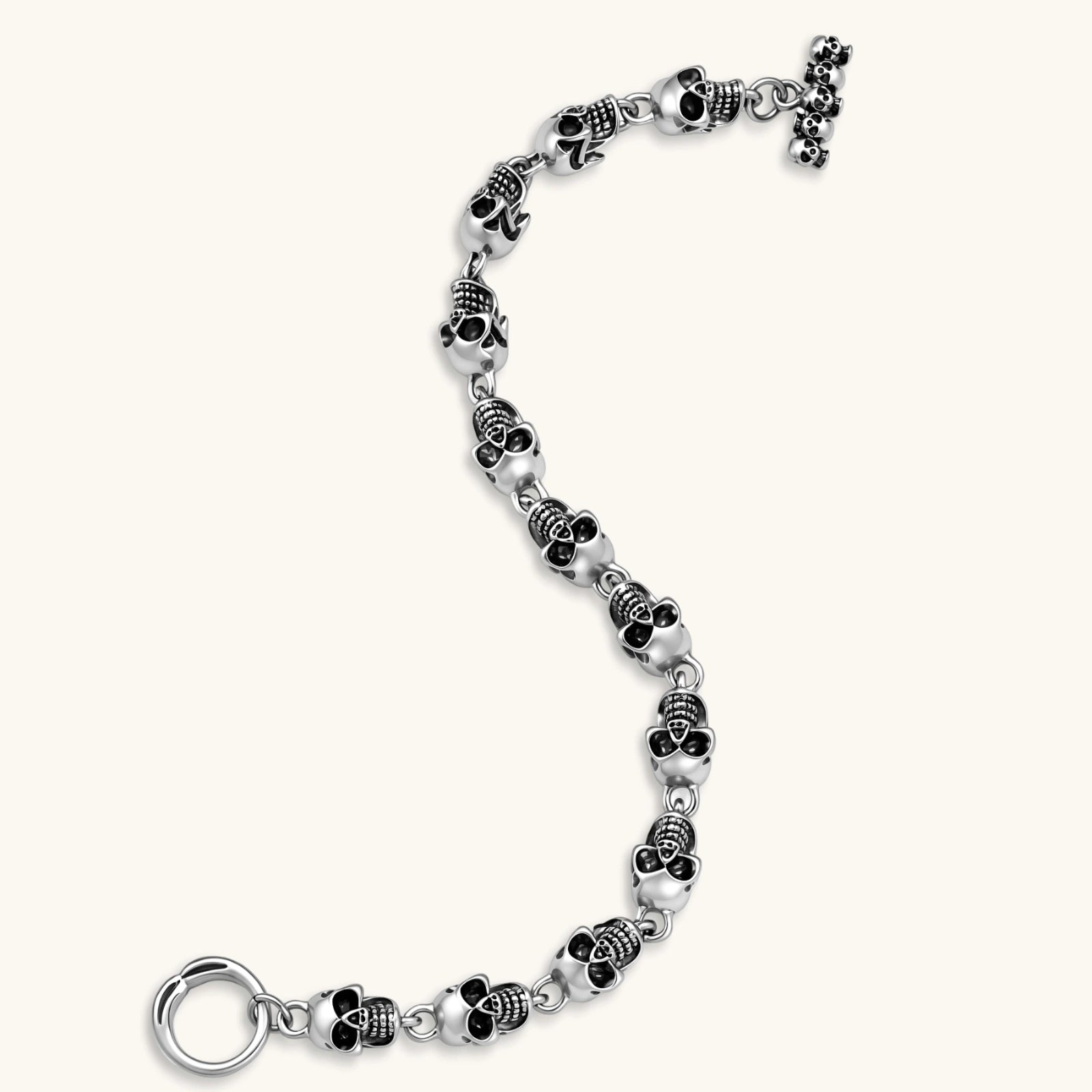 Silver stainless steel bracelet with linked 3D skull charms and a spring-ring clasp, oxidized black detailing, 225mm length.