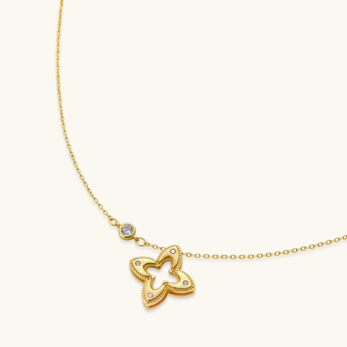 18K gold-plated 925 silver necklace with open four-petal flower pendant, CZ accents, bezel-set stone on chain, white background.