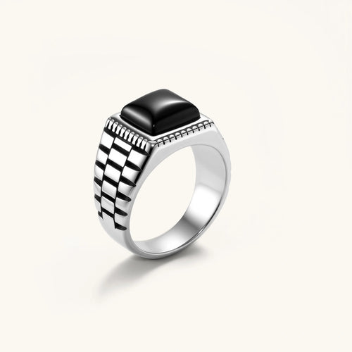 Silver stainless steel signet ring with checkered band texture, beaded border, and square black onyx cabochon stone center.